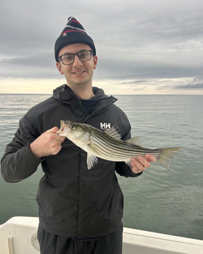 Ryan holding a striped bass on a boat on the Chesapeake Bay
